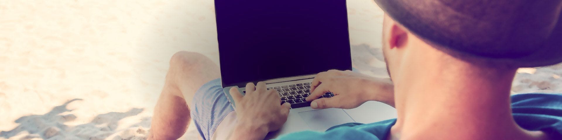 Homem na praia com computador portátil